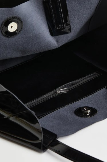 Γυναικεία μαύρη τσάντα shopper από υψηλής ποιότητας γυαλιστερό συνθετικό δέρμα. Αυτή η τσάντα shopper είναι μεσαίου μεγέθους και κλείνει με μαγνητικό κούμπωμα. Υπάρχει μια ενιαία μεγάλη θήκη και εσωτερική τσέπη που κλείνει με φερμουάρ. Διαθέτει δύο λαβές